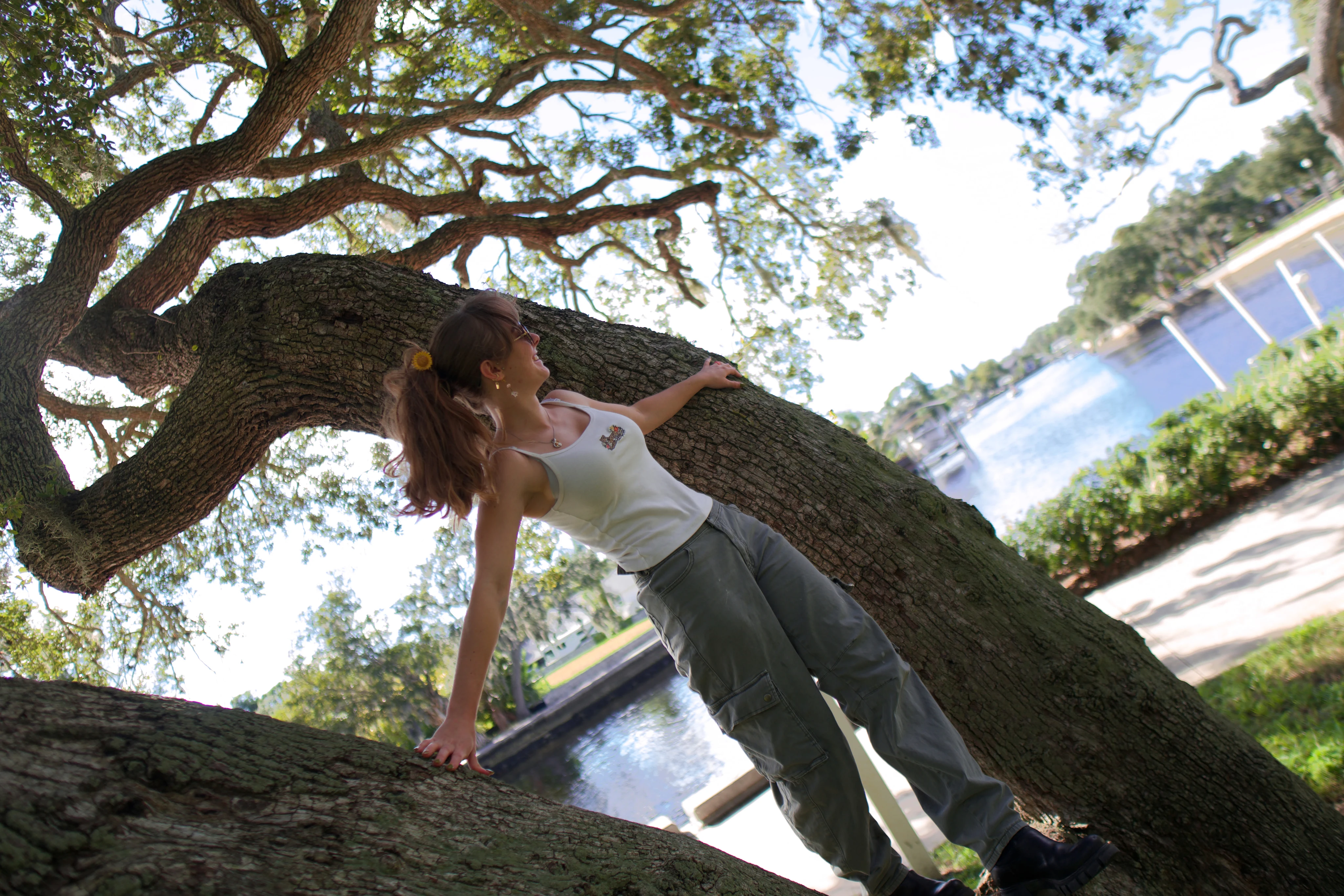 A woman braced against a leaning oak trunk with her hair swinging