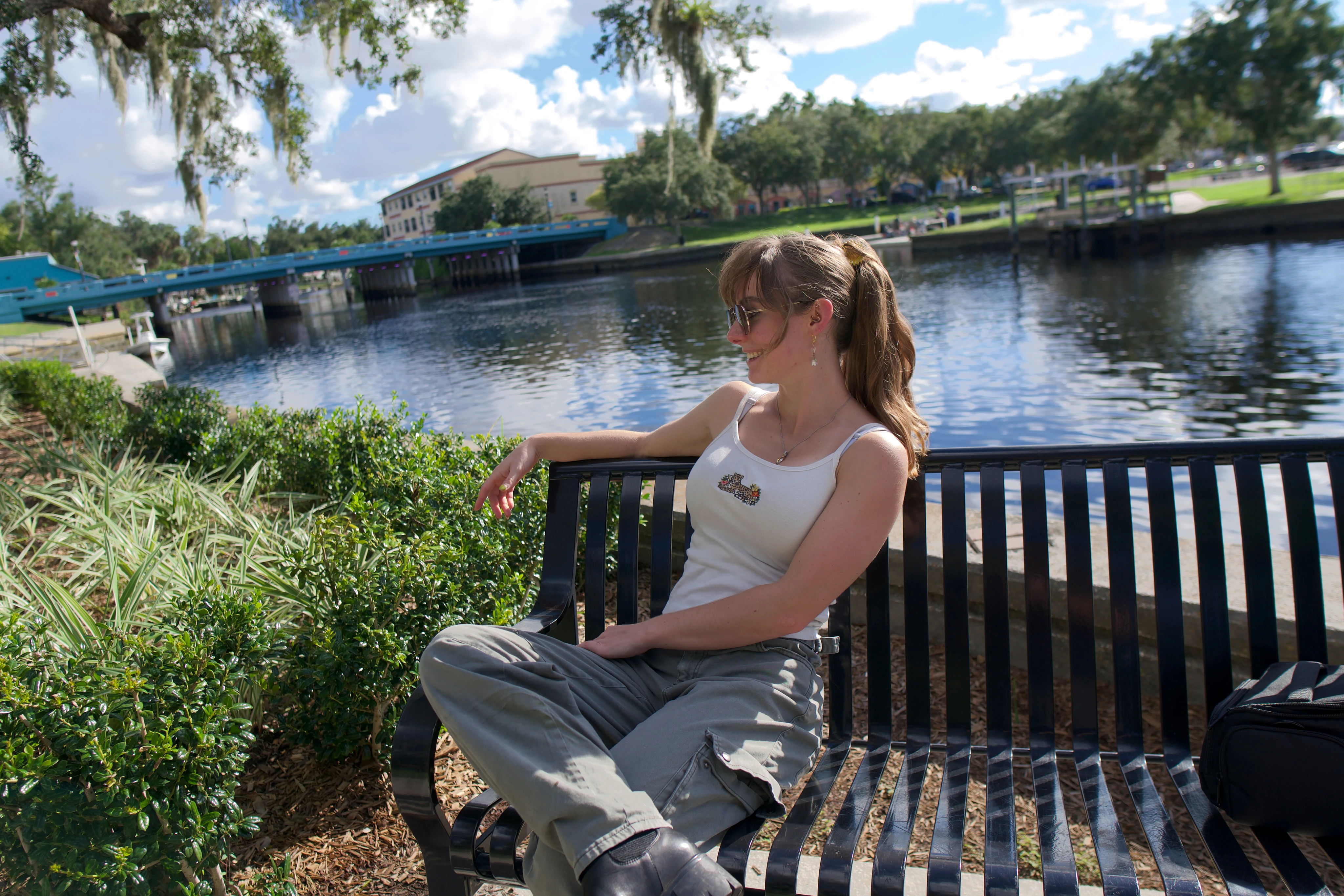 A woman on a waterside bench looking toward the marina
